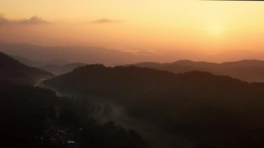 Güzel bir gündoğumu sırasında vadide sisle birlikte dağın üzerinden hava görüntüsü. Yüksek kalite 4k görüntü