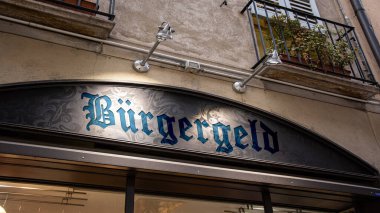 Resimde Almanca 'da vatandaşlık yönünü gösteren bir tabela ve işaret var..