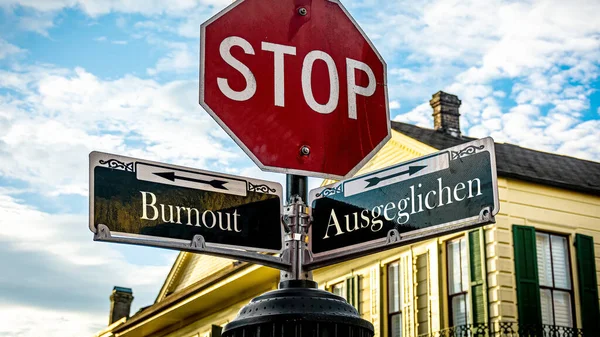 stock image An image with a signpost pointing in two different directions in German. One direction points to Balanced, the other points to Burnout