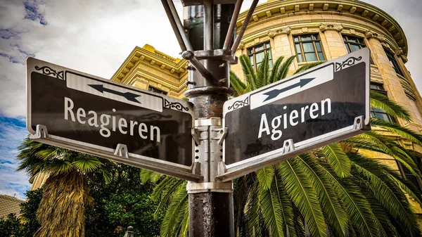 stock image An image with a signpost pointing in two different directions in German. One direction points to act, the other points to react.