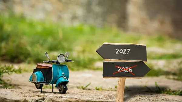 stock image An image with a signpost pointing in two different directions in German. One direction points to 2027, the other points to 2026.