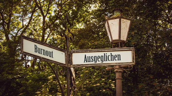 stock image An image with a signpost pointing in two different directions in German. One direction points to Balanced, the other points to Burnout