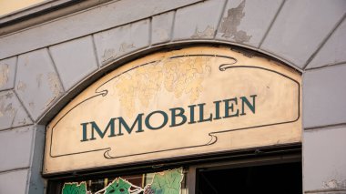 Resim bir tabela ve Almanca gayrimenkul olduğunu gösteren bir tabela gösteriyor..