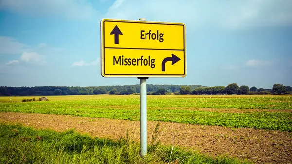 stock image An image with a signpost pointing in two different directions in German. One direction points to success, the other points to failure.