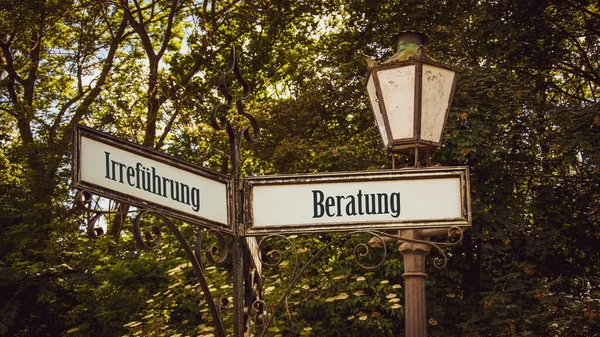 stock image An image with a signpost pointing in two different directions in German. One direction points to counsel, the other points to deception.