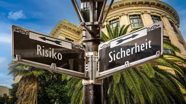 stock image An image with a signpost pointing in two different directions in German. One direction points to safety, the other points to risk.