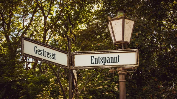 stock image An image with a signpost pointing in two different directions in German. One direction points to Relaxed, the other points to Stressed.