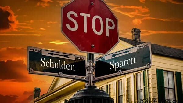 stock image An image with a signpost pointing in two different directions in German. One direction points to savings, the other points to debt.