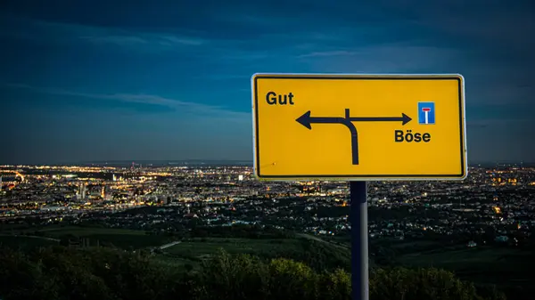 stock image An image with a signpost pointing in two different directions in German. One direction points to good, the other points to evil.