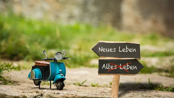 stock image An image with a signpost pointing in two different directions in German. One direction points to New Life, the other points to Old Life.