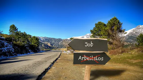 Stock image An image with a signpost pointing in two different directions in German. One direction points to Job, the other points to Unemployed.