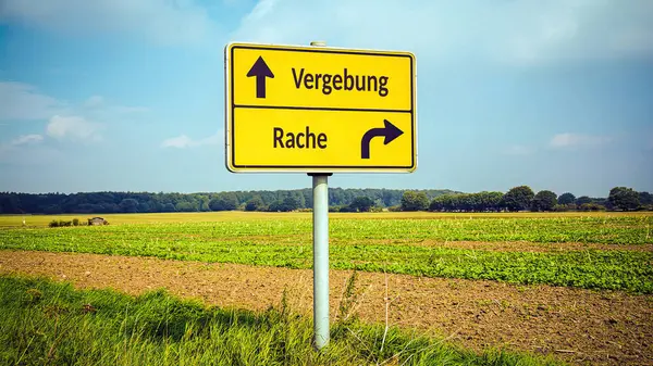 stock image An image with a signpost pointing in two different directions in German. One direction points to forgiveness, the other points to revenge.