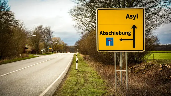 stock image An image with a signpost pointing in two different directions in German. One direction points to asylum, the other points to deportation.