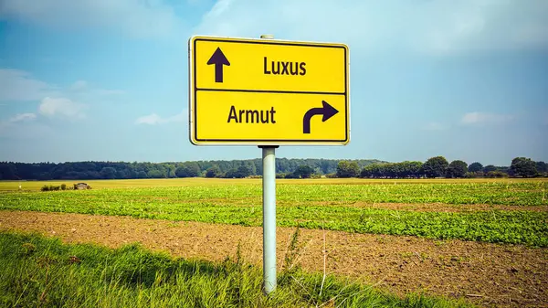 stock image An image with a signpost pointing in two different directions in German. One direction points to luxury, the other points to poverty.