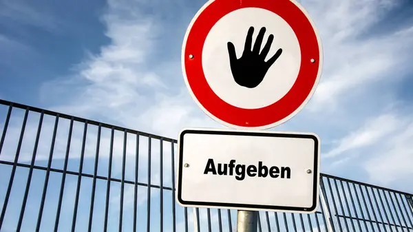 stock image An image with a signpost pointing in two different directions in German. One direction points to picking up, the other pointing to giving up.