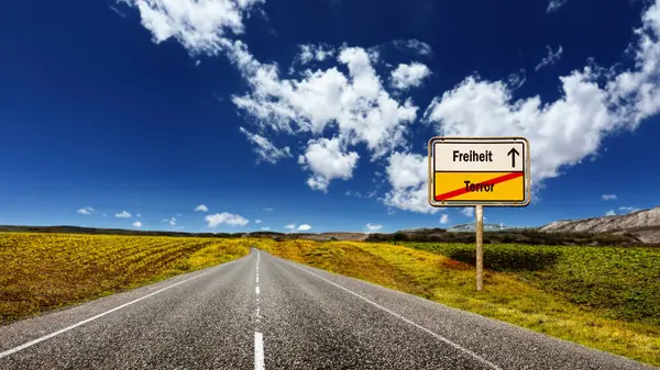 stock image An image with a signpost pointing in two different directions in German. One direction points to freedom, the other points to terror.