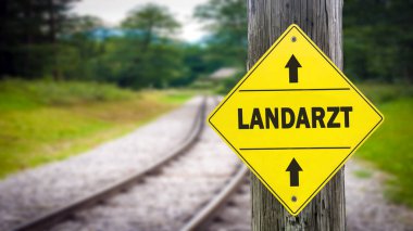 Almanca köy doktorunun yönüne işaret levhaları olan bir resim.