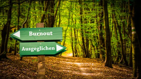 stock image An image with a signpost pointing in two different directions in German. One direction points to Balanced, the other points to Burnout