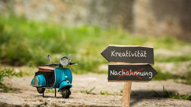 Almanca 'nın iki farklı yönünü gösteren işaret direği olan bir resim. Bir yön yaratıcılığı gösteriyor, diğeri de taklidi..