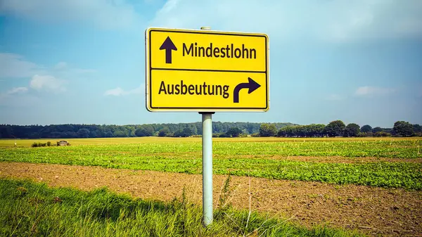 stock image An image with a signpost pointing in two different directions in German. One direction points to minimum wage, the other points to exploitation.