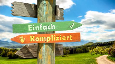 An image with a signpost pointing in two different directions in German. One direction points to Simple, the other points to Complicated. clipart