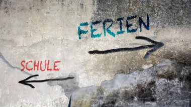 Almanca 'nın iki farklı yönünü gösteren işaret direği olan bir resim. Bir yön tatilleri gösterir, diğeri okulu gösterir..