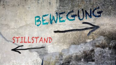 Almanca 'nın iki farklı yönünü gösteren işaret direği olan bir resim. Bir yön hareketi işaret eder, diğeri ise duraksamayı..