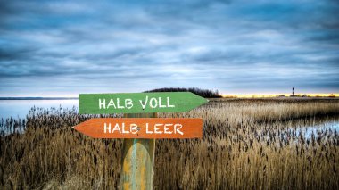 An image with a signpost pointing in two different directions in German. One direction points half full, the other points half empty. clipart