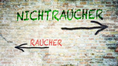 Almanca 'nın iki farklı yönünü gösteren işaret direği olan bir resim. Bir yön sigara içmeyenleri, diğeri sigara içenleri gösteriyor..