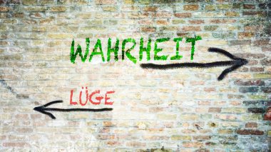 Almanca 'nın iki farklı yönünü gösteren işaret direği olan bir resim. Bir yön gerçeği gösterir, diğeri yalanı..
