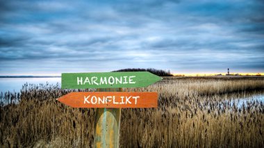 An image with a signpost pointing in two different directions in German. One direction points to harmony, the other points to conflict. clipart