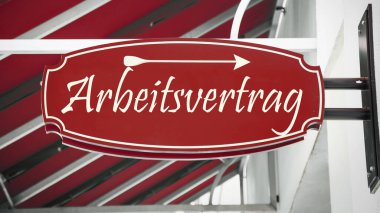 Görüntü, Almanca bir istihdam sözleşmesi yönünde bir tabela ve işaret gösteriyor..