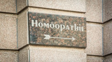 Resimde Almanca homeopati yönünü gösteren bir tabela ve işaret var..