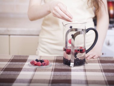 Mutfak masasında böğürtlenlerle içki hazırlıyorum.