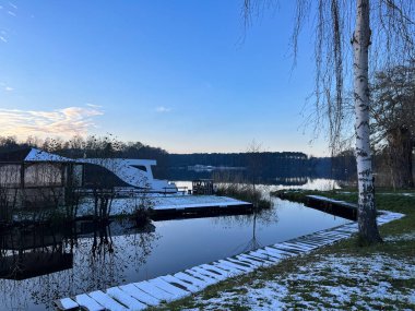 Kışın göl kıyısında. Bir park. Kar yağıyor. Kış akşamı.