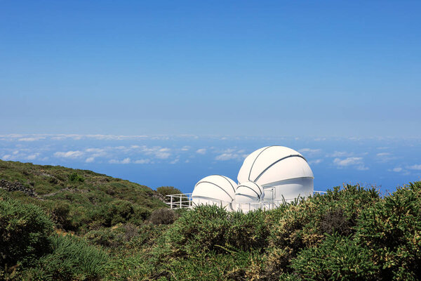 Telescope set in the mountains of El Roque de los Muchachos National Park on the island of La Palma on a sunny day aginst a backgroun of clouds. Horizontal view. Copy space.