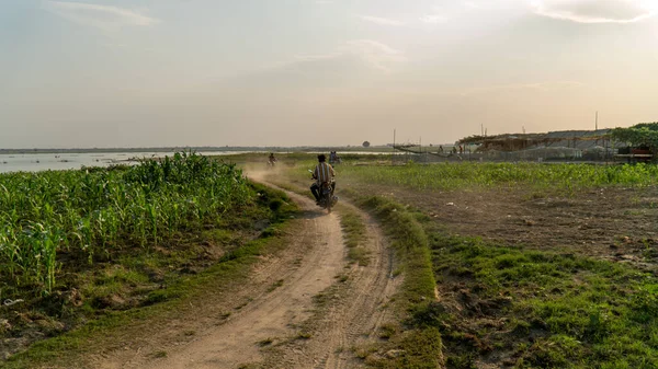 Mandalay, Myanmar - 3 / 8 / 2020: Asyalı adam U Bein Köprüsü yakınlarındaki toprak yolda motosiklet sürüyor