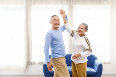 Romantik ve neşeli Asyalı son sınıf çifti dans etmekten ve müziğe el ele tutuşmaktan keyif alır. Oturma odasında gülümseme ve mutlulukla birlikte. Evde yaşlılar için emeklilik etkinliği.