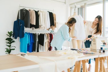 Asyalı kadın moda tasarımcısı ya da mankene kağıt kumaş desenleri tutturmaya yardım eden terzi. Terzi atölyesinde çalışan ve müşteriler için yeni moda koleksiyonları tasarlayan bir terzi..