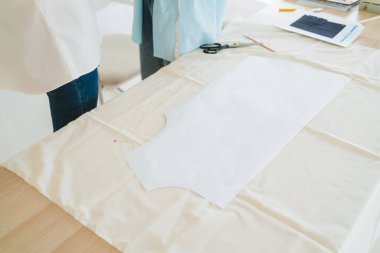 Masadaki kumaşın üzerindeki kağıt desenini tutturmak. Terzi ya da moda tasarımcısı terzi ya da atölyedeki lağım temizleyicisi yeni koleksiyon giysileri için çalışıyor. Fotoğraf alanı kopyala.