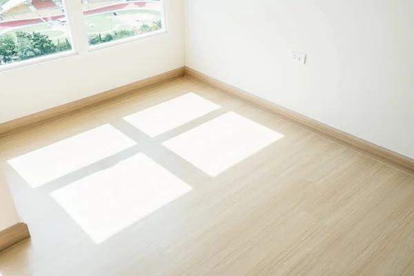 Stock image Empty room closeup on an engineering wooden floor with sunlight from the window. Minimalist interior design and real estate for decoration. Real image with copy space.