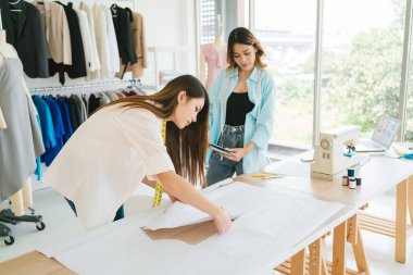 Terzi ya da moda tasarımcısının elbise deseni yapmak için makasla kağıt kestiği eli kapatın. Moda tasarımcısı ya da atölyedeki lağım temizleyicisi yeni koleksiyon giysileri için çalışıyor..