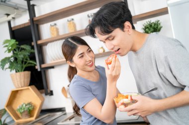 Genç ve sağlıklı bir Asyalı çift, gülümseme ve mutluluk dolu bir gülümsemeyle taze bir domatesi birlikte besliyor. Sağlıklı ve vejetaryen yemek reklamı olan aktif bir yaşam tarzı. Kopyalama alanı olan resim.