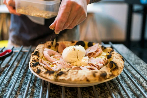 Napoli usulü pizza: Pizzanın üzerinde ezilmiş şam fıstığı ve burrata pizzası ile çeşnilendirilmiş şefin el yapımı. Burrata ve mortadella 'ya odaklan. İtalyan usulü Napoli pizzası..