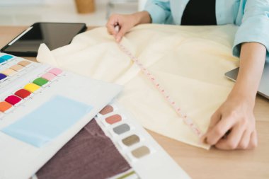 Kadın moda tasarımcısının ya da terzi el ölçüm kağıdının elleri. Kıyafet modeli yapmak için şeritli. Moda tasarımcısı atölyede yeni bir koleksiyon için çalışıyor..