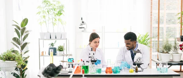 Portraits of a diversity of scientists working together in a research laboratory. Group of chemistry students working in the laboratory with the microscope and chemical liquid in beakers.