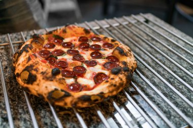 Napoli usulü pizza: servis etmeden önce mutfak tezgahındaki pizza rafında sosis doğrayan şefin eli. İtalyan usulü taze Napoli pizzası..