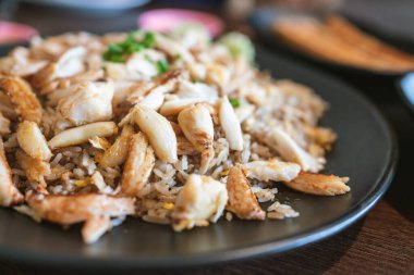 Fried rice with full-loaded fresh chunks of crab, fried with high-temperature Chinese style for a smoked smell. Served with sliced scallion and cucumber. Chinese and Thai style food in Bangkok.