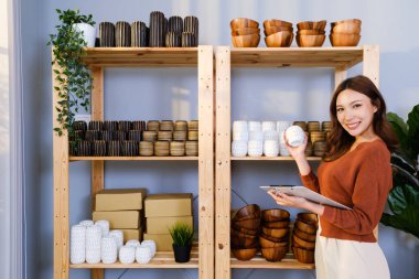 Asyalı güzel bir kadın evde canlı yayında el yapımı vazo satıyor. Genç çekici kız satmadan önce stok ve mal stoğunu kontrol ediyor. Uzak satın alma ve satın alma kavramı.