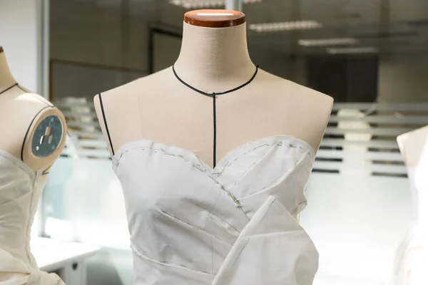 Tailor's textile female mannequin with black lines covered with canvas fabric pattern and draping for dressmakers working and designing new fashion collections in an atelier tailor workshop.